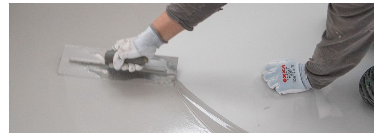 Persoon welke met een vlakspaan gietvloer reparatie aanbrengt